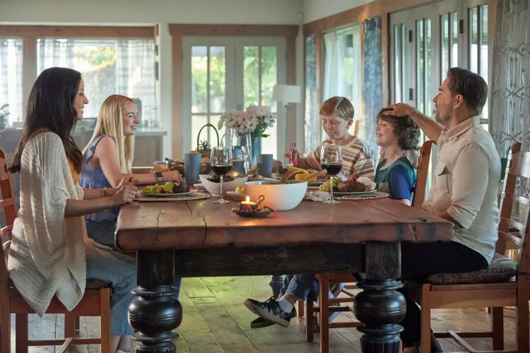 A family sitting around a dinner table, enjoying a meal and each other’s company. From Hallmark's "Big Sky River: The Bridal Path" 