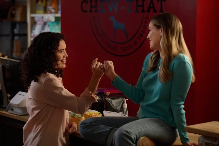 Two women inside a store, smiling and doing a fist bump.