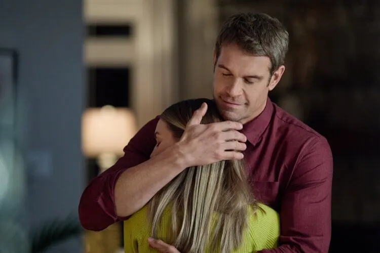 A man in a red shirt hugging a woman, both showing a tender moment.