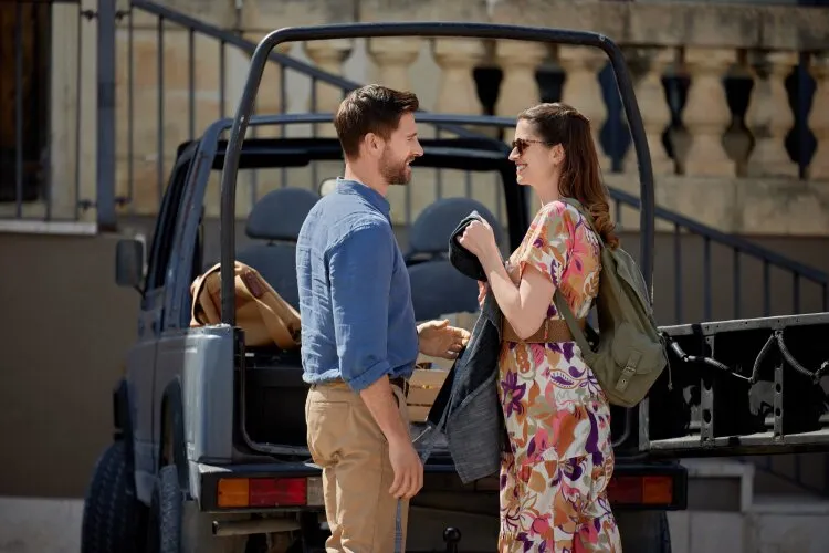  A man and a woman talking and smiling near a vehicle with an open back. From Hallmark's "For Love & Honey"
