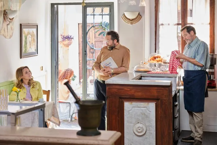 Three people in a cozy Italian café, engaged in a conversation near the counter.  "Two Scoops of Italy"  on Hallmark.