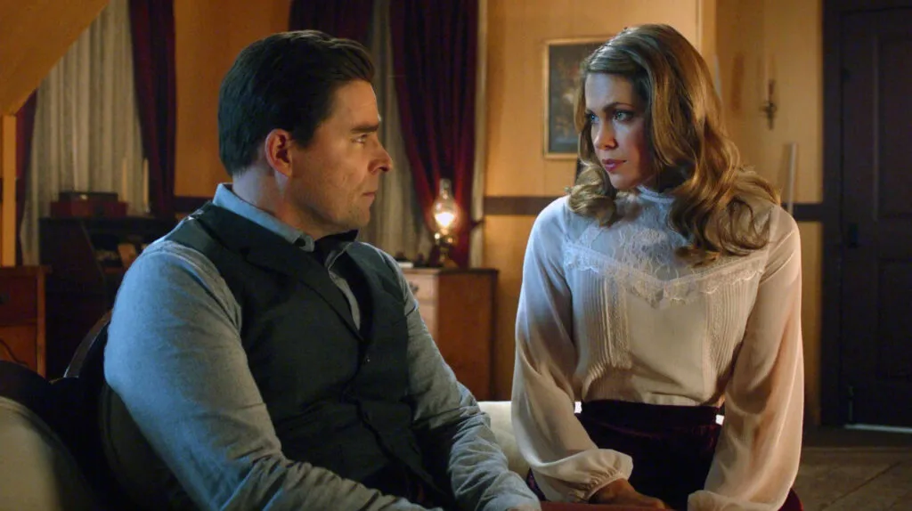 Rosemary comforts a sad Lee on the couch beneath a warm lighting.