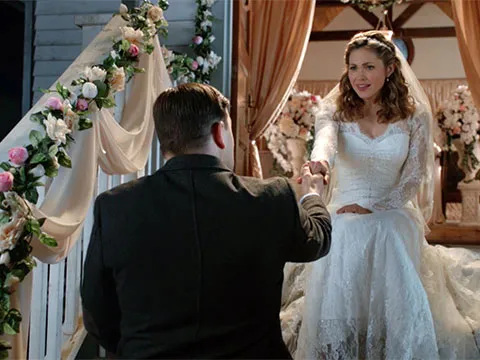 Lee holds out his hand for Rosemary who is wearing a wedding dress on the church steps.