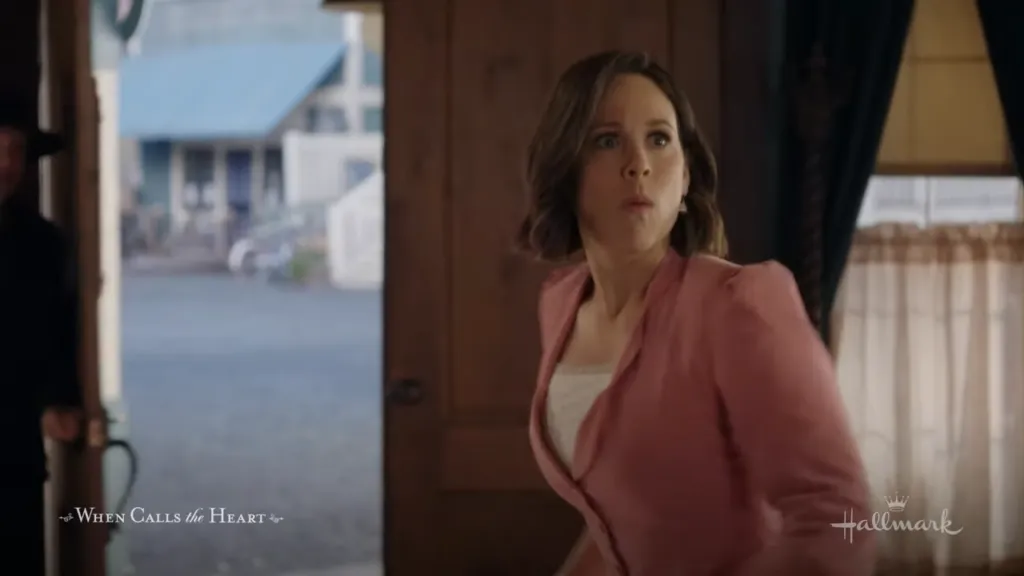 Elizabeth Thatcher surprised: Elizabeth Thatcher looks surprised as she peeks from behind a doorway in a rustic setting.
