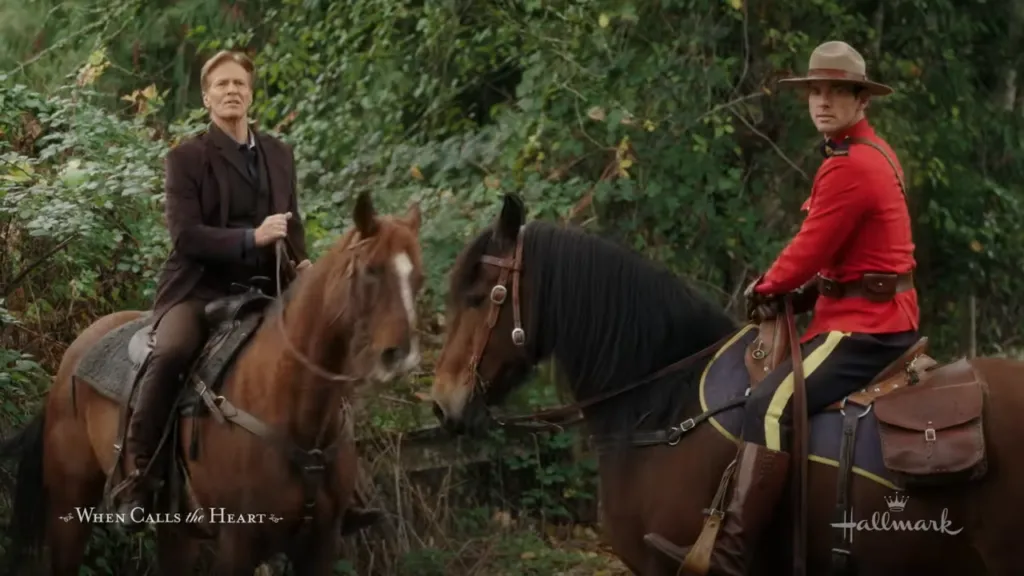 Bill Avery and Nathan Grant on horseback: Bill Avery and Nathan Grant are riding horses in a wooded area, Bill in a brown outfit and Nathan in his red Mountie uniform. "Run to You When Calls the Heart"
