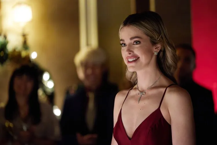 Hallmark Movie's "Operation Nutcracker": In this elegant scene, a woman dressed in a striking red gown radiates happiness at what appears to be a festive gathering or event. Her joyful expression and attentive gaze, possibly directed towards a speaker or performer, capture a moment of delight and engagement. The soft, warm lighting and holiday decorations in the background, including twinkling lights and seasonal greenery, enhance the festive and sophisticated atmosphere. This image likely portrays her as a central figure in a holiday celebration, embodying the spirit of joy and community that defines the season.