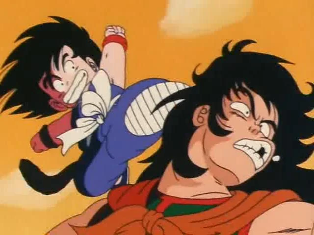 A dynamic shot from Dragon Ball featuring young Goku mid-air delivering a powerful kick to Yamcha. Goku, wearing his blue training outfit and white sash, has a determined and fierce expression. Yamcha, clad in his orange and green outfit, grimaces in pain as the attack connects with his face. The background is a bright orange sky, emphasizing the intensity of the battle. Classic early Dragon Ball energy and humor radiate from this moment.