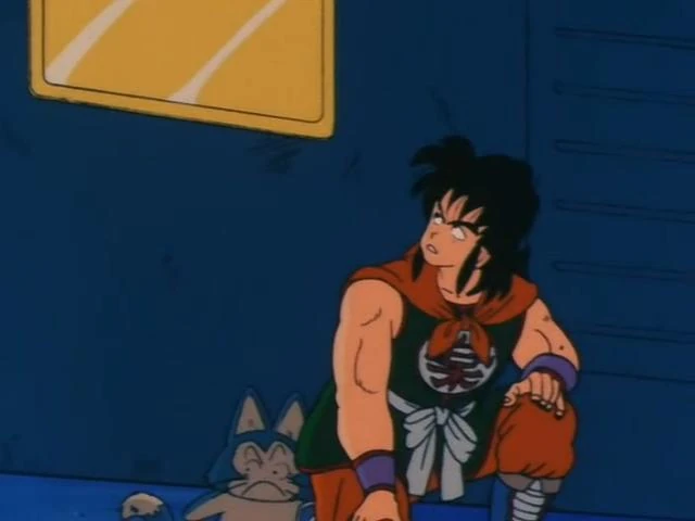A reflective scene from Dragon Ball featuring Yamcha and Puar. Yamcha is crouched down, looking to the side with a cautious and serious expression, dressed in his signature black and orange outfit with a kanji symbol on his chest. Puar, his loyal blue cat-like companion, sits nearby, appearing calm and relaxed. The setting is a simple blue wall with a yellow-framed window, creating a quiet and introspective atmosphere. The scene suggests a moment of planning or concern during one of their adventures.