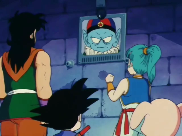 Bulma, Goku, Yamcha, and Oolong confront Emperor Pilaf, who appears on a monitor with an angry expression. The group stands in a stone-walled room, with Bulma raising her fist in frustration.