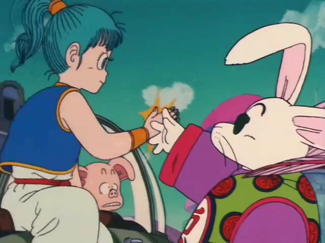 Bulma, with blue hair and wearing a blue and white outfit, slaps hands with Monster Carrot, a white rabbit wearing sunglasses and a colorful robe. Oolong, a pig character, looks on with a shocked expression from a nearby vehicle. The background features a green sky.