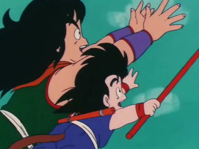 Yamcha and Goku, with determined expressions, leap through the air. Yamcha reaches forward while Goku wields his Power Pole, both focused on their target. The background features a green sky with wisps of clouds.