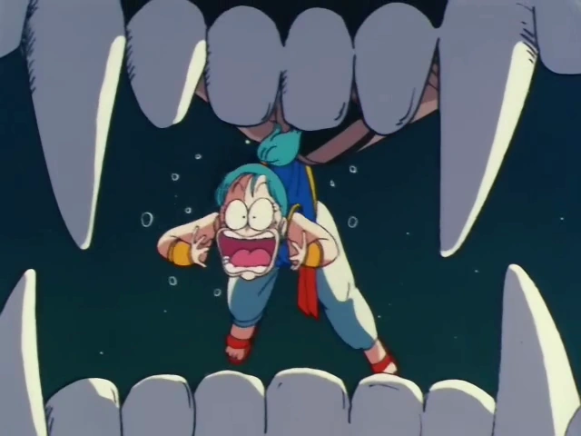 Bulma screams in panic as she dangles between the large, sharp teeth of Goku's Great Ape transformation, with the night sky in the background.