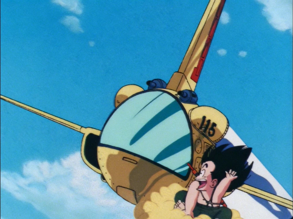 Goku rides the Flying Nimbus with a joyful expression, flying close to a yellow aircraft marked '115' against a bright blue sky with scattered clouds.