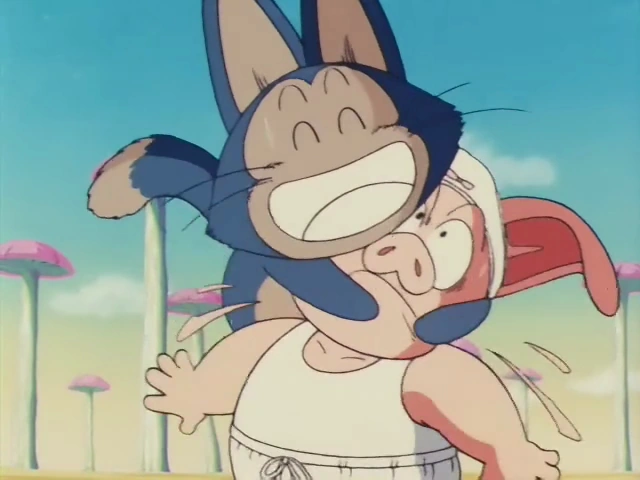 Puar playfully pounces on Oolong, wrapping around his face with a big smile, while Oolong looks surprised and flustered. The desert landscape with mushroom-shaped trees is visible in the background under a sunny sky.