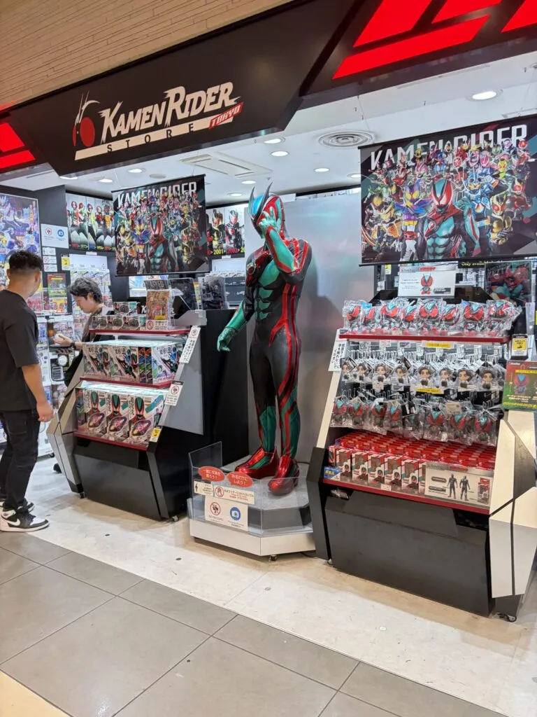 Kamen Rider Store Japan shelves featuring Kamen Rider figures, posters, and a full-size Rider statue display inside Tokyo Station Ichibangai.