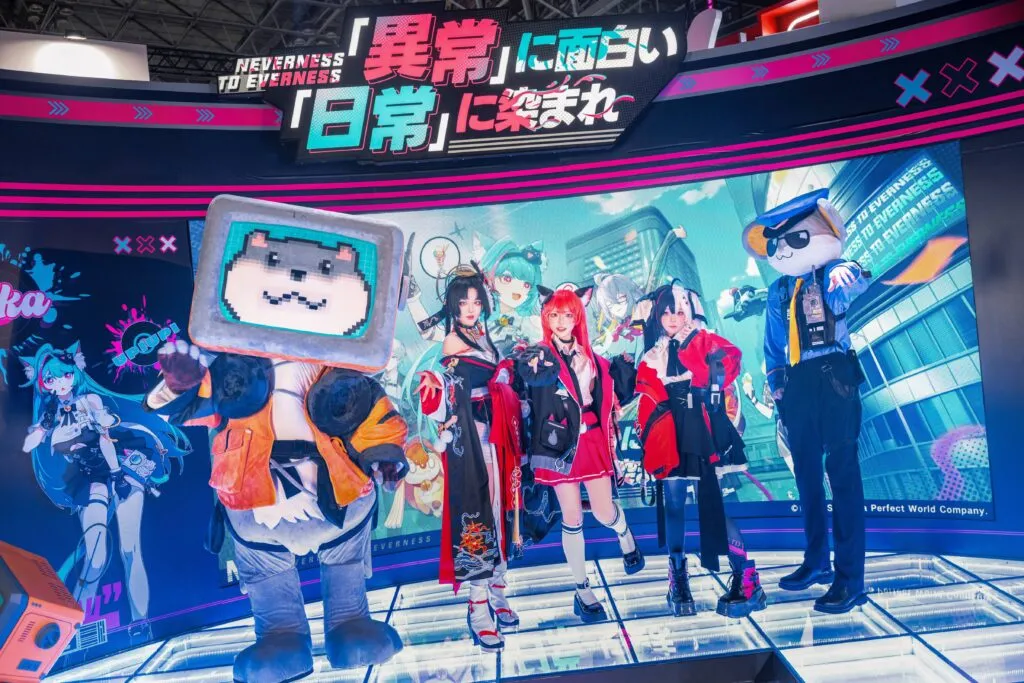 The NTE game booth at Tokyo Game Show 2025 featuring cosplayers dressed as anime-style characters and mascots, including a TV-headed dog and police mascot, with a colorful neon backdrop promoting the game.