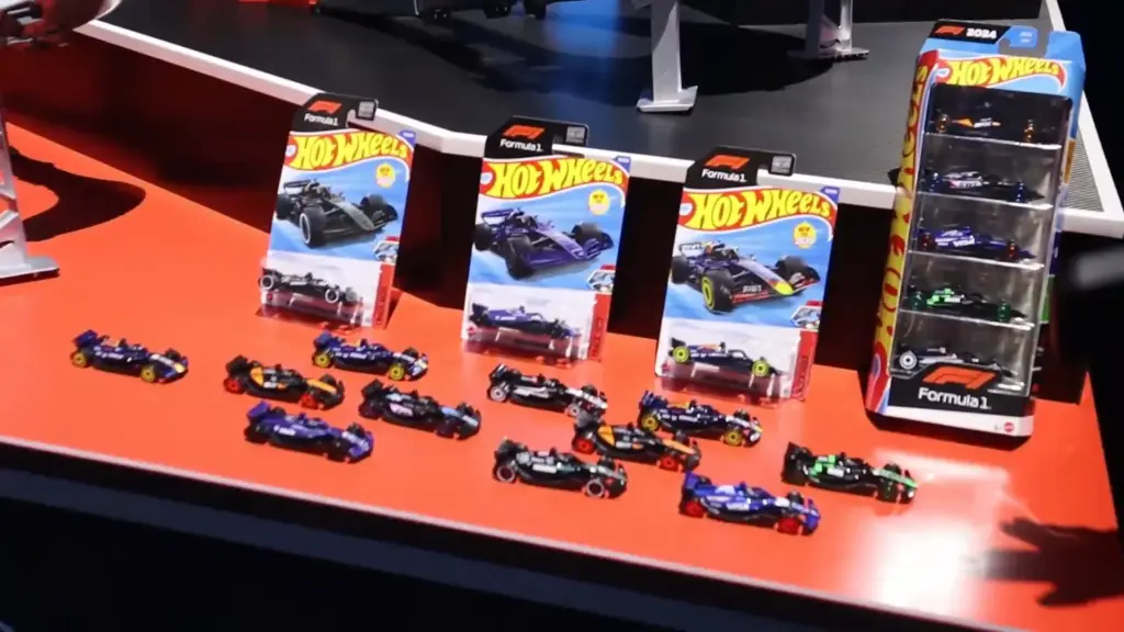 Hot Wheels Formula 1 die-cast cars from the Toy Fair NY 2025 Mattel showcase, with racecars and collector packs arranged on a bright red display table.