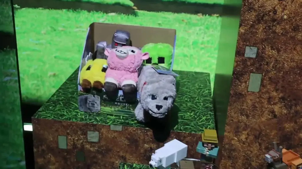 Minecraft plush toys featured at the Toy Fair NY 2025 Mattel showcase, including sheep, wolves, and creeper characters displayed on grassy block-themed stands.