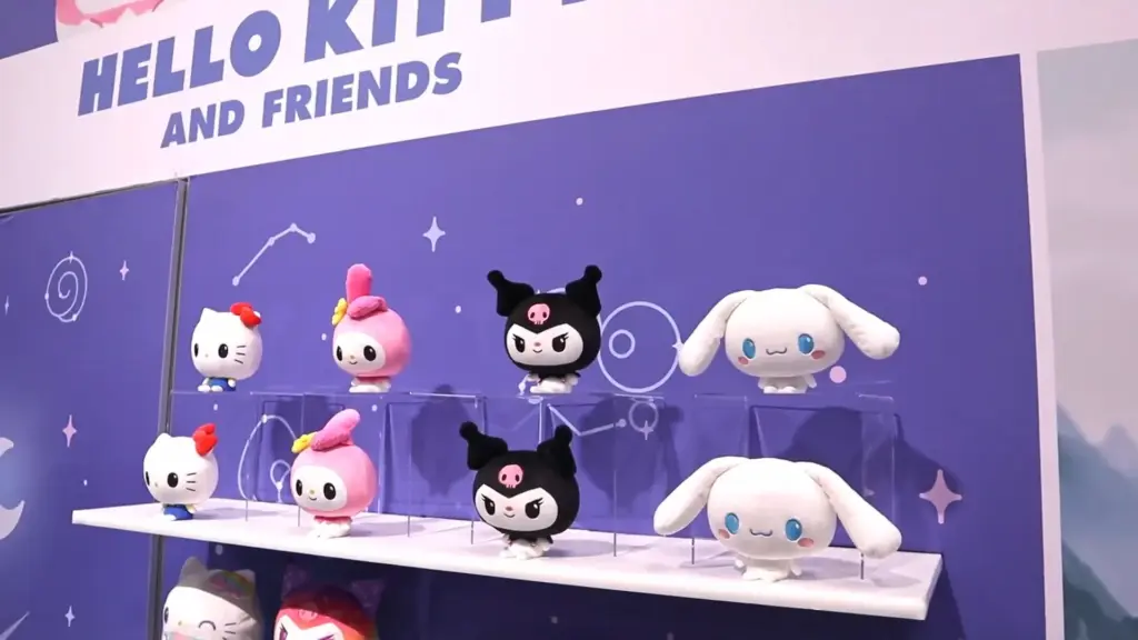 A Hello Kitty and Friends display featuring TeeTurtle reversible plushies of Hello Kitty, My Melody, Kuromi, and Cinnamoroll arranged neatly on clear shelves at Toy Fair NY 2025.