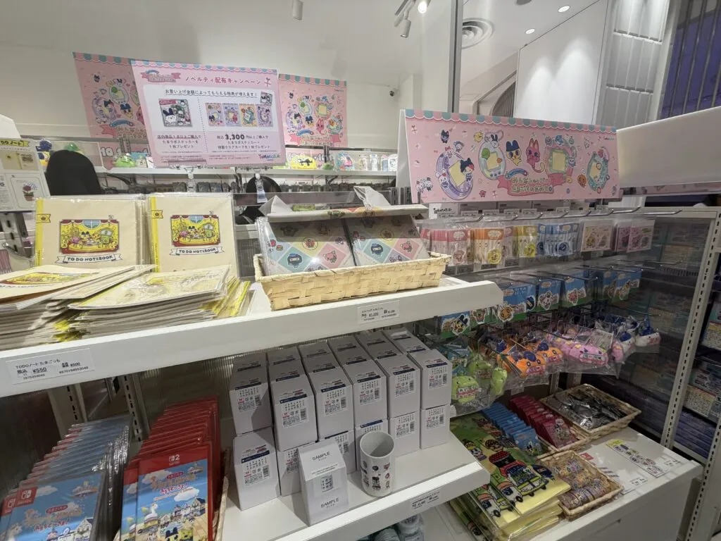 A close-up view of the Tamagotchi merchandise shelves showcasing various collectibles, including plush toys, boxes, and charms.