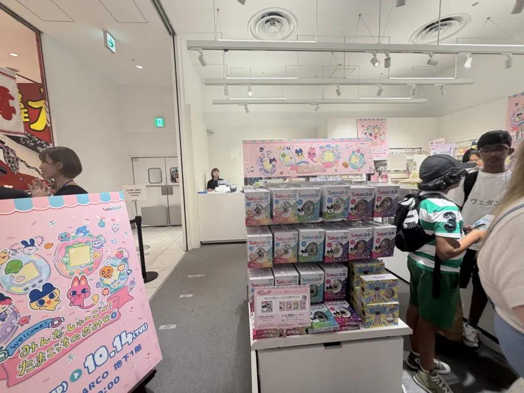 Display shelves packed with Tamagotchi-themed notebooks, mugs, stationery, and colorful accessories neatly organized.