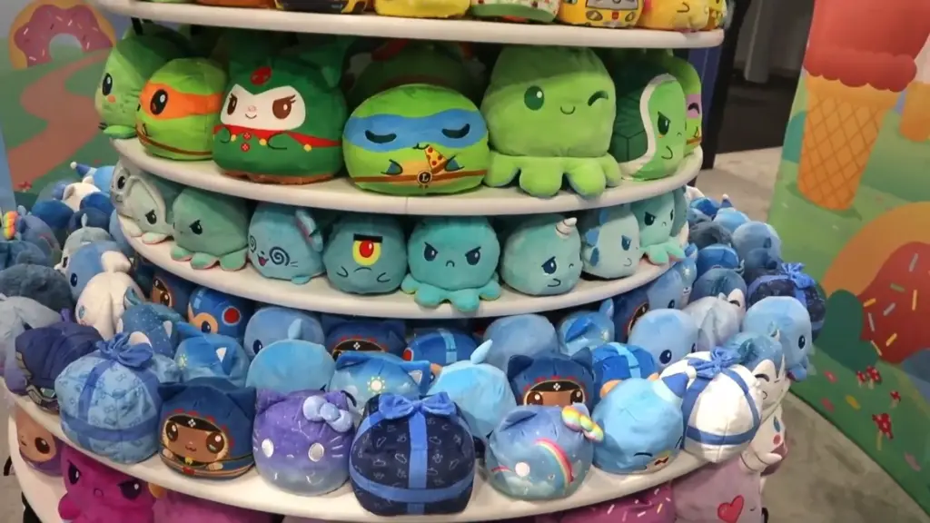 A colorful round display stand filled with TeeTurtle reversible plushies featuring various characters like octopuses, turtles, and fandom icons in green, blue, and purple tones at Toy Fair NY 2025.