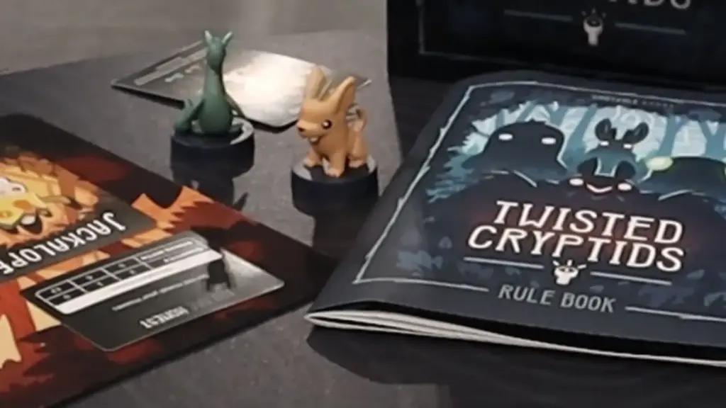 Close-up of Twisted Cryptids mini figures and rulebook at the Toy Fair NY 2025 Unstable Games showcase, featuring detailed sculpts of creatures like the Jackalope and Nessie.
