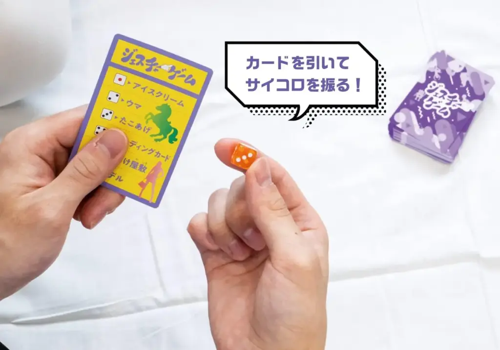 Hands holding a BEVERLY Gesture Game card and an orange die, showing the step where a player draws a card and rolls the dice to decide which gesture topic to act out.