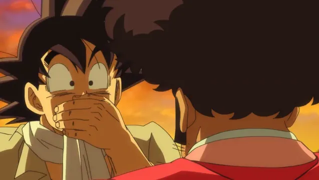 Goku covering his mouth in surprise while facing Mr. Satan, who is seen from behind in his red suit, with a warm sunset sky glowing in the background.