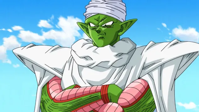 Piccolo standing with his arms crossed, wearing his white cape and turban, looking stern against a bright blue sky with clouds.