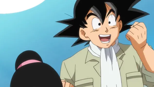 Goku smiling with excitement and raising a clenched fist in the air, wearing his light-colored jacket and scarf, with Chi-Chi’s head partially visible in the foreground against a bright blue sky.
