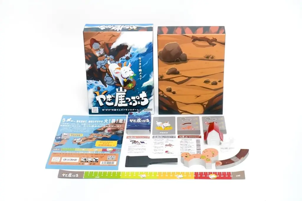 Jelly Jelly Games Goat Cliff Edge Balance Game Yagi Gakeppuchi box with all components laid out, including the game box, instruction cards, measuring ruler, cliff board pieces, goat figure, house piece, and colorful balancing tokens.
