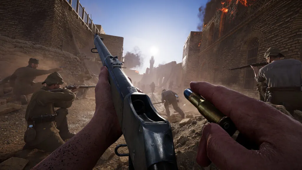 First-person view of a soldier reloading a rifle in a war-torn street, with teammates taking cover and firing as smoke and debris fill the area.